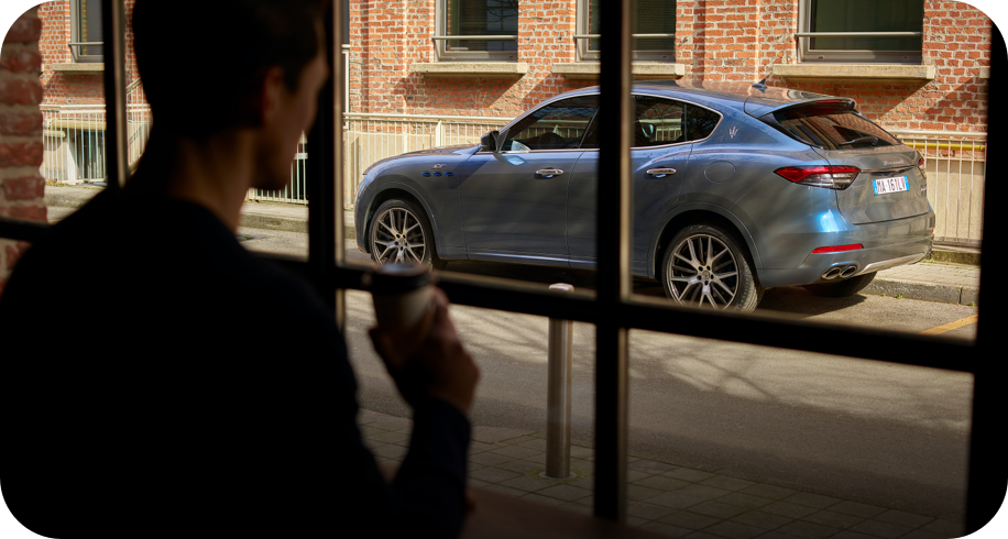 Mann schaut durch ein Fenster auf einen maserati